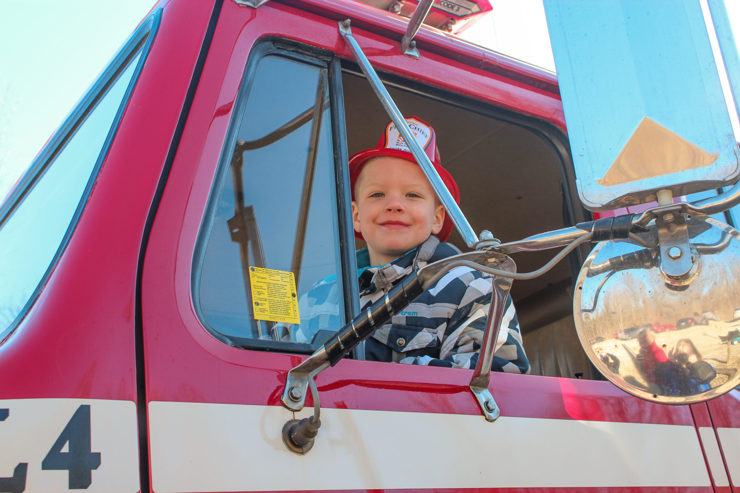 A child sitting in the driver seat of a firetruck