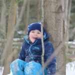 Child enjoying nature winter camp tiffin leaning against tree