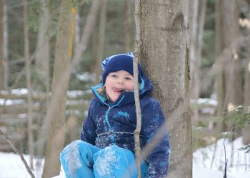 Child enjoying nature winter camp tiffin leaning against tree